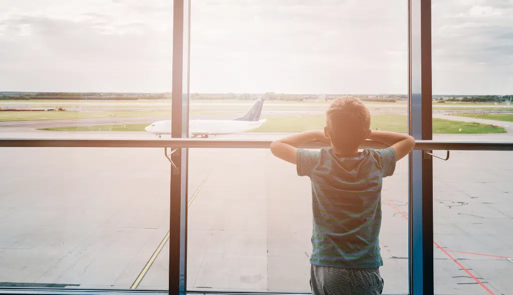 Enfant regardant la fenêtre un avion décollé